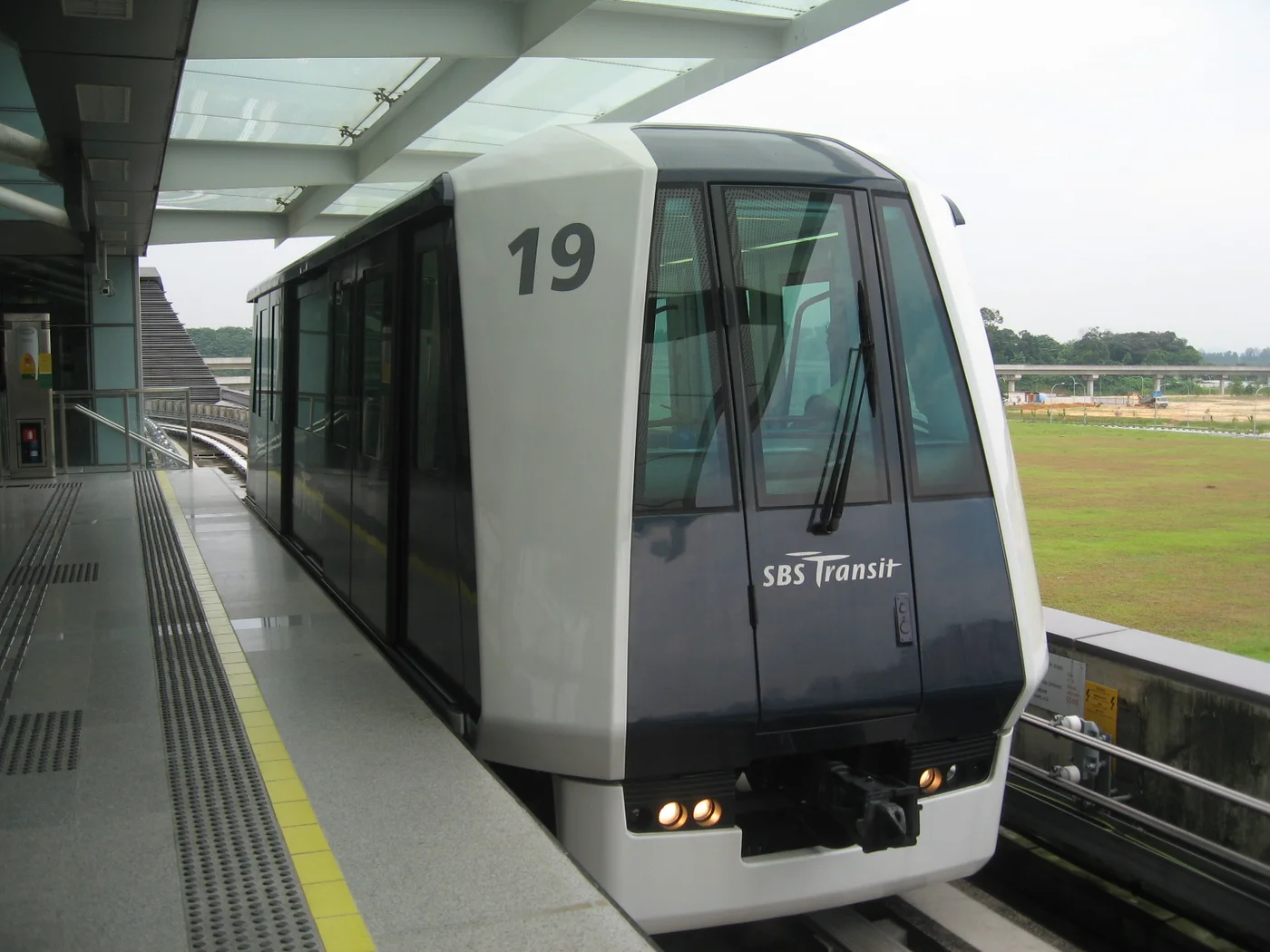 A single-car Punggol LRT train at the platform in June 2006, with open ground beyond the tracks.